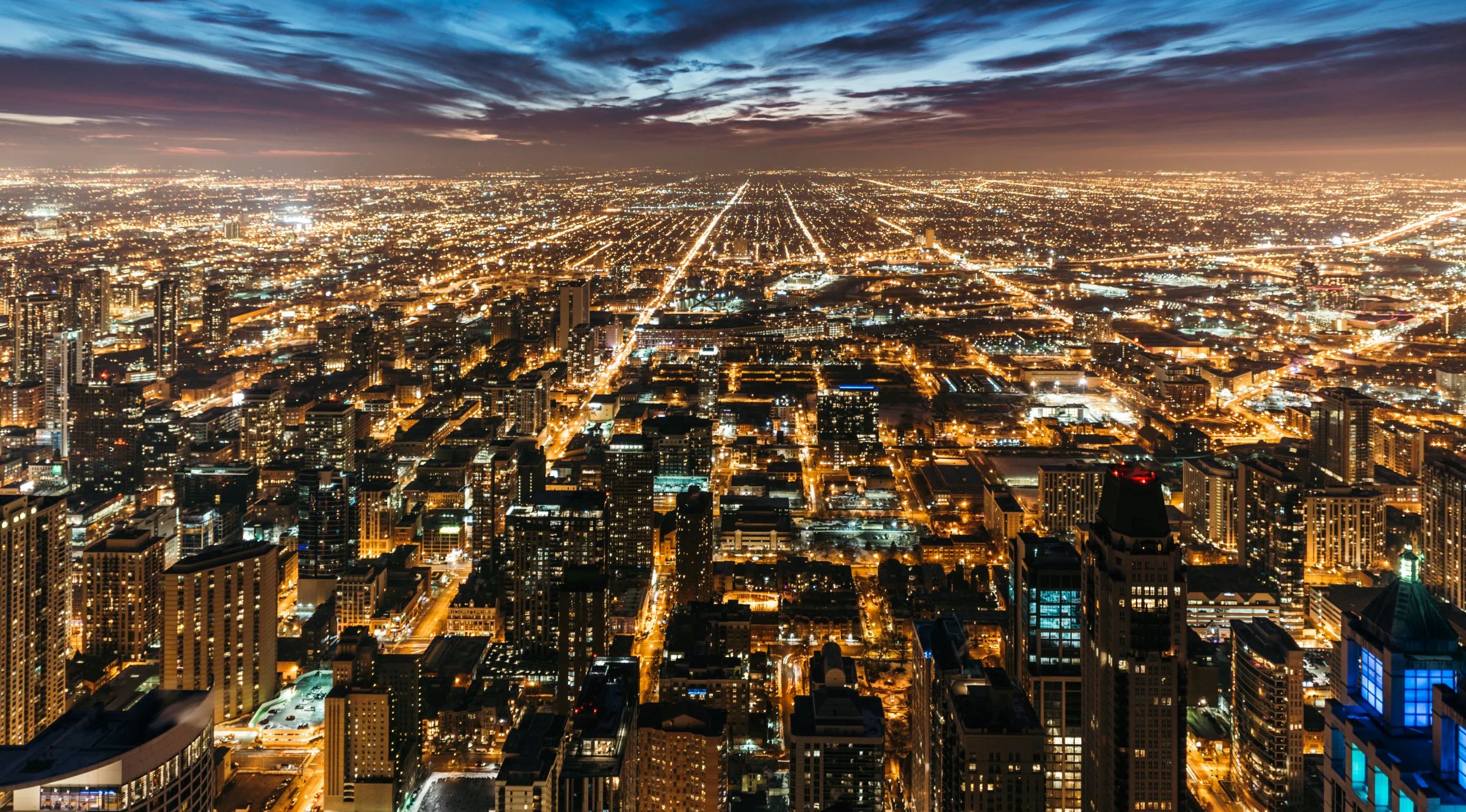 Cityscape at night with many lights from homes, businesses, roads.