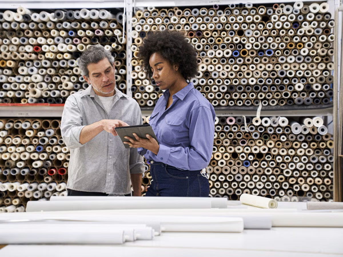 Two people using tablet surrounded by fabric