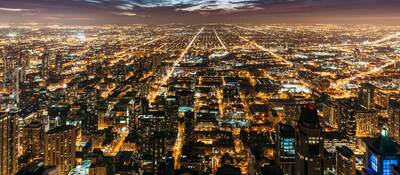 Cityscape at night with many lights from homes, businesses, roads.