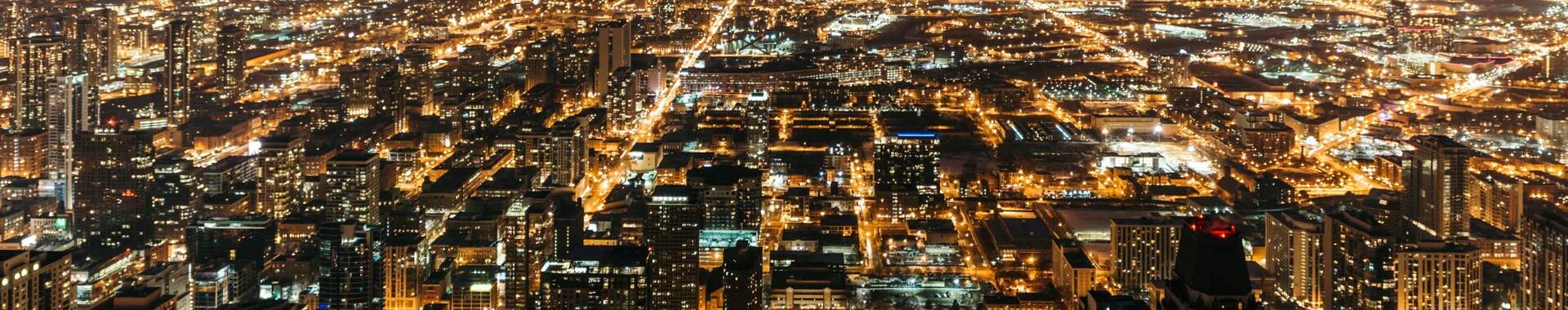 Cityscape at night with many lights from homes, businesses, roads.